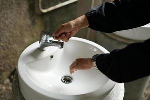 wassen handen in een openbaar wassen, minimalistische wit wastafel met chroom kraan foto