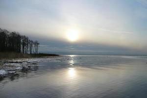 verkoudheid winter zon blijft hangen laag over- de horizon, zeegezicht foto
