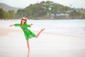 mooi weinig meisje in jurk Bij strand hebben plezier. grappig meisje genieten zomer vakantie. foto