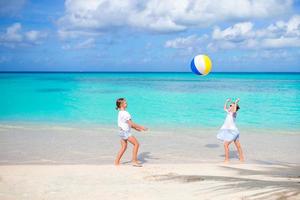 weinig aanbiddelijk meisjes spelen met bal Aan de strand foto