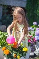 weinig kleuter meisje gieter bloemen met een gieter kan foto