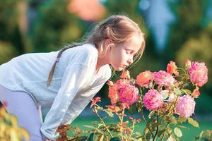 weinig aanbiddelijk meisje ruiken kleurrijk bloemen Bij zomer dag foto