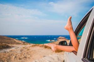 zomer vakantie, vakantie, reis, weg reis en mensen concept - dichtbij omhoog van weinig meisje voeten tonen van auto venster foto