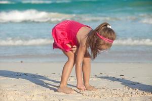 weinig schattig meisje trekt Aan de wit zand Bij tropisch strand foto