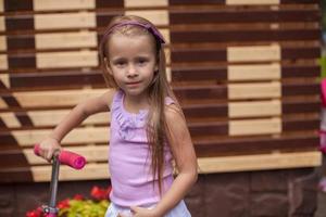 aanbiddelijk weinig meisje Aan een scooter in kinderen park foto