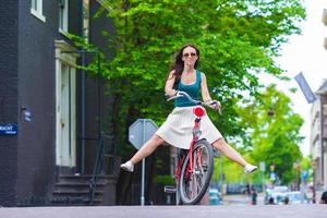 jong gelukkig vrouw Aan fiets in Europese stad foto