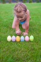 mooi weinig meisje telt Pasen eieren Aan groen gras foto