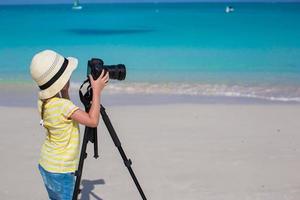 weinig meisje het schieten met camera Aan statief gedurende haar zomer vakantie foto