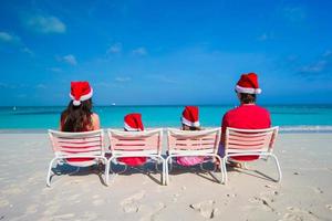 gelukkig familie van vier in de kerstman hoed Aan zomer vakantie foto