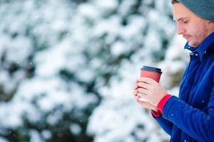 jong Kaukasisch Mens drinken heet koffie in bevroren winter dag buitenshuis foto