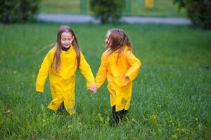 aanbiddelijk weinig meisjes onder de regen Aan warm herfst dag foto