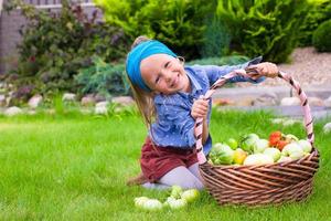portret van weinig meisje met herfst oogst van tomaat in manden foto