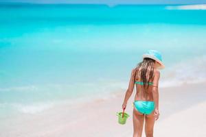 aanbiddelijk weinig meisje spelen met strand speelgoed Aan wit tropial strand foto