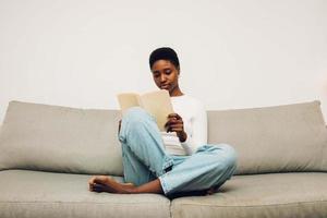 zwart vrouw lezing Aan een sofa foto