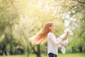 weinig glimlachen meisje spelen en knuffelen puppy in de park foto