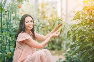 jong vrouw Holding een mand van groen en ui in de kas foto