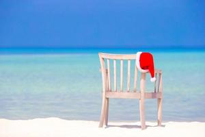 rood de kerstman hoed Aan strand stoel Bij tropisch vakantie foto