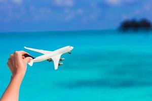 klein wit miniatuur van een vliegtuig Aan achtergrond van turkoois zee foto