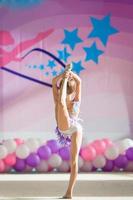 weinig mooi gymnast Aan tapijt. aanbiddelijk gymnast doet mee in wedstrijden in ritmisch gymnastiek foto