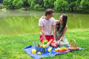 jong gelukkig paar picknicken en ontspannende buitenshuis foto