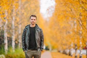 jong Mens drinken koffie met telefoon in herfst park buitenshuis foto