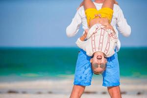 weinig meisje en gelukkig vader hebben pret gedurende strand vakantie foto