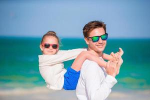 weinig meisje en gelukkig vader hebben pret gedurende strand vakantie foto