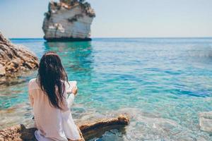 jong vrouw lezing Aan tropisch wit strand foto