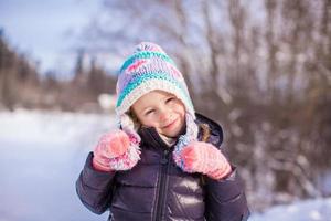 portret van weinig aanbiddelijk meisje in winter hoed Bij besneeuwd Woud foto