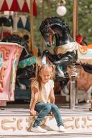 aanbiddelijk weinig meisje in de buurt de carrousel buitenshuis foto