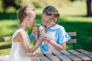 weinig meisjes aan het eten ijsje buitenshuis Bij zomer in buitenshuis cafe foto