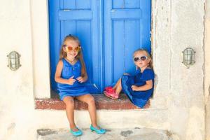 weinig schattig zussen zittend in de buurt oud blauw deur in Grieks dorp van emporio, Santorini foto