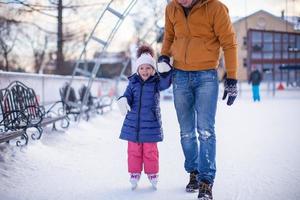 close-up van schattig klein meisje met jonge vader op de ijsbaan foto