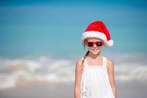 schattig klein meisje in kerstmuts op tropisch strand foto