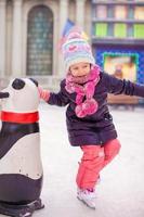 schattig gelukkig meisje genieten van schaatsen op de ijsbaan foto