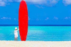 aanbiddelijk weinig meisje met groot surfboard gedurende tropisch vakantie foto