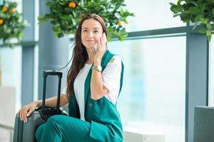 portret van jong vrouw met smartphone in Internationale luchthaven. vliegmaatschappij passagier in een luchthaven lounge aan het wachten voor vlucht vliegtuig foto