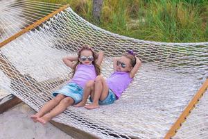 weinig zoet meisjes ontspannende in hangmat Aan zomer vakantie foto