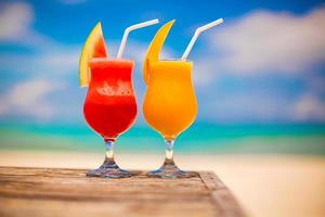 twee cocktails vers watermeloen en mango Aan achtergrond van verbijsterend turkoois zee foto