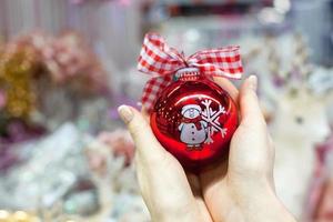mooi rood bal in handen van jong vrouw voor Kerstmis foto