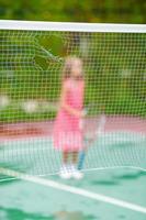 klein meisje dat tennis speelt op de baan foto