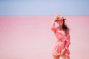 vrouw in hoed wandelen Aan een roze zout meer Aan een zonnig zomer dag. foto