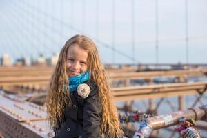 aanbiddelijk weinig meisje zittend Bij Brooklyn brug foto