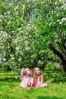 aanbiddelijk weinig meisjes hebben pret in bloeiende appel boom tuin foto