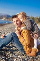 portret van een aanbiddelijk meisje knuffelen zijn jong vader Bij de strand foto