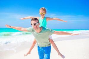 weinig meisje en gelukkig vader hebben pret gedurende strand vakantie foto