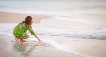 schattig klein meisje veel plezier op tropisch strand tijdens vakantie foto