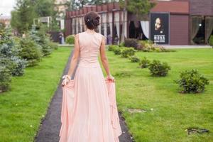 terug visie van mooi jong vrouw in een lang jurk Bij de ceremonie buitenshuis foto