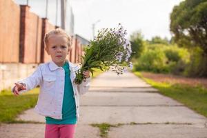 weinig meisje wandelen buitenshuis met bloemen foto