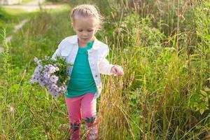 weinig schattig meisje wandelen met een boeket van bloemen foto